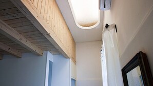 A room with a sloped ceiling, a door, and a mirror on the wall. - Palazzo Nicastro Guest House Blue (Avola)