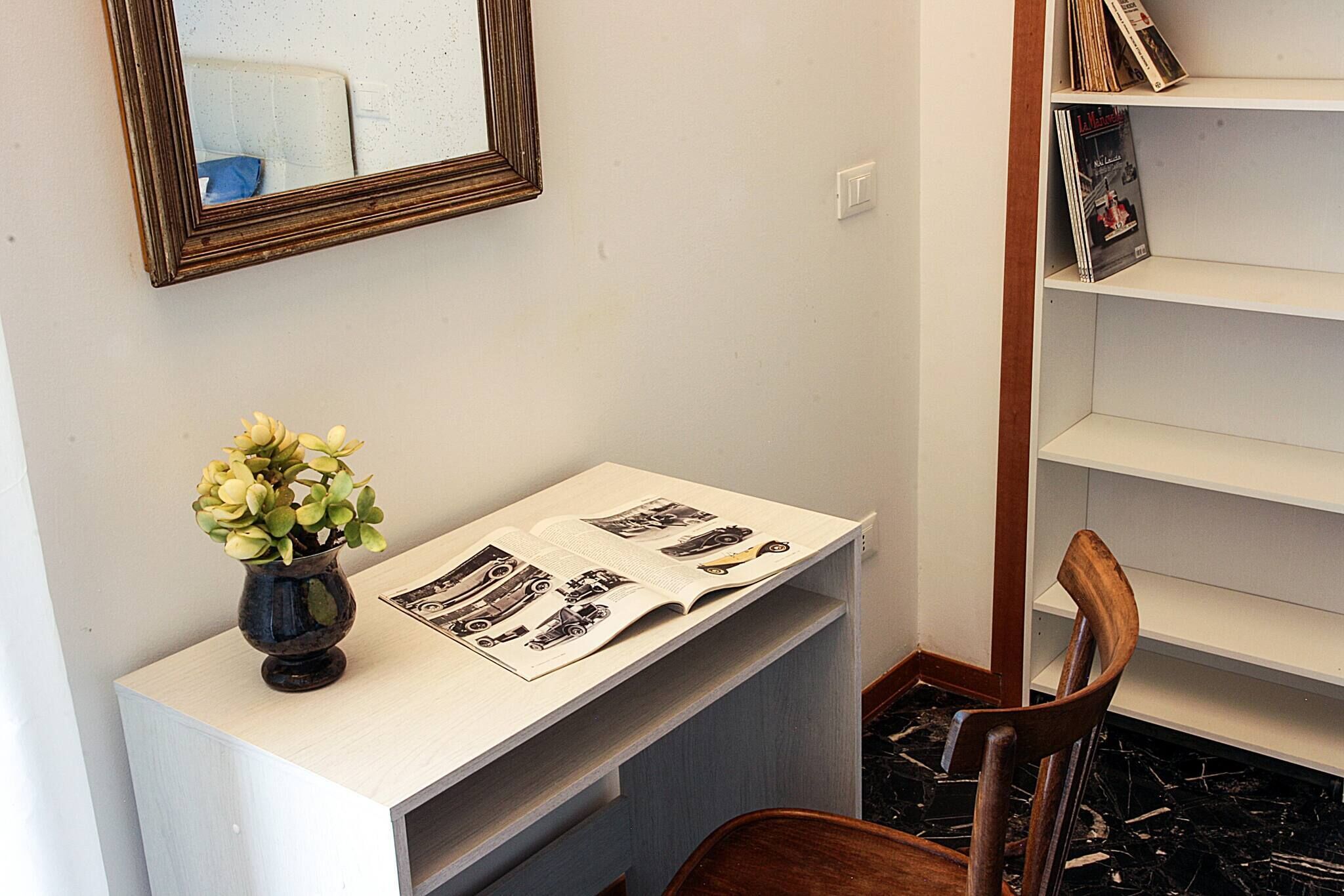 Ein Schreibtisch mit Blumen, einer Zeitschrift und einem Spiegel an der Wand.