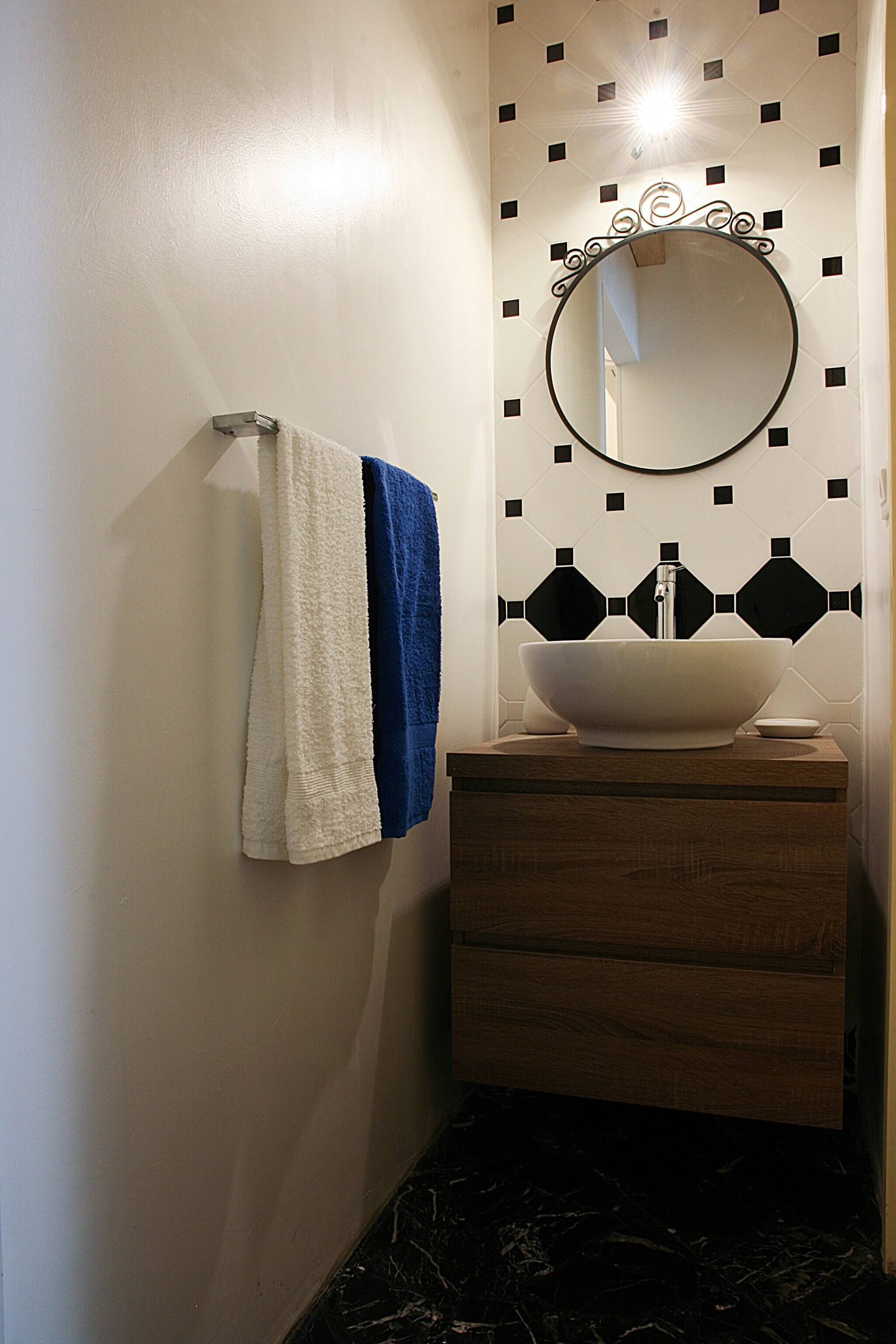 Ein Badezimmer mit einem weißen Waschbecken, einem Spiegel und einem Handtuchhalter.