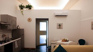 A compact kitchen with a stove, sink, and a small dining area with a table and chairs. - Palazzo Nicastro Guest House Blue (Avola)