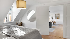 A bedroom with a large bed, a round mirror, and a ceiling light.