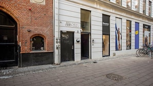 A building with a brick facade, a black door, and a storefront with mannequins.