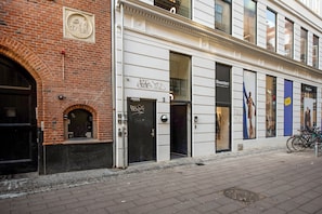 Um edifício com fachada de tijolos, porta preta e vitrine com manequins.