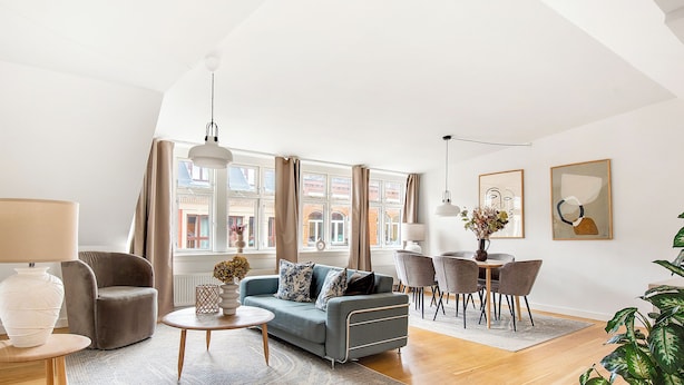 A modern living room with a sofa, chairs, a coffee table, and a dining area.