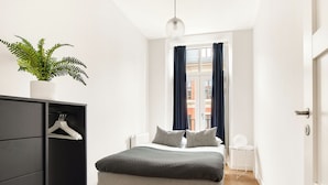Une chambre à coucher moderne avec un lit, une armoire, une petite table et une plante en pot.