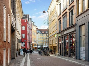 A narrow street lined with historic buildings, some with visible signage for businesses like a kitchen and dining establishment. - Leaves 2- Chic Apt for 8 Persons in Central Copenhagen (Copenhagen)
