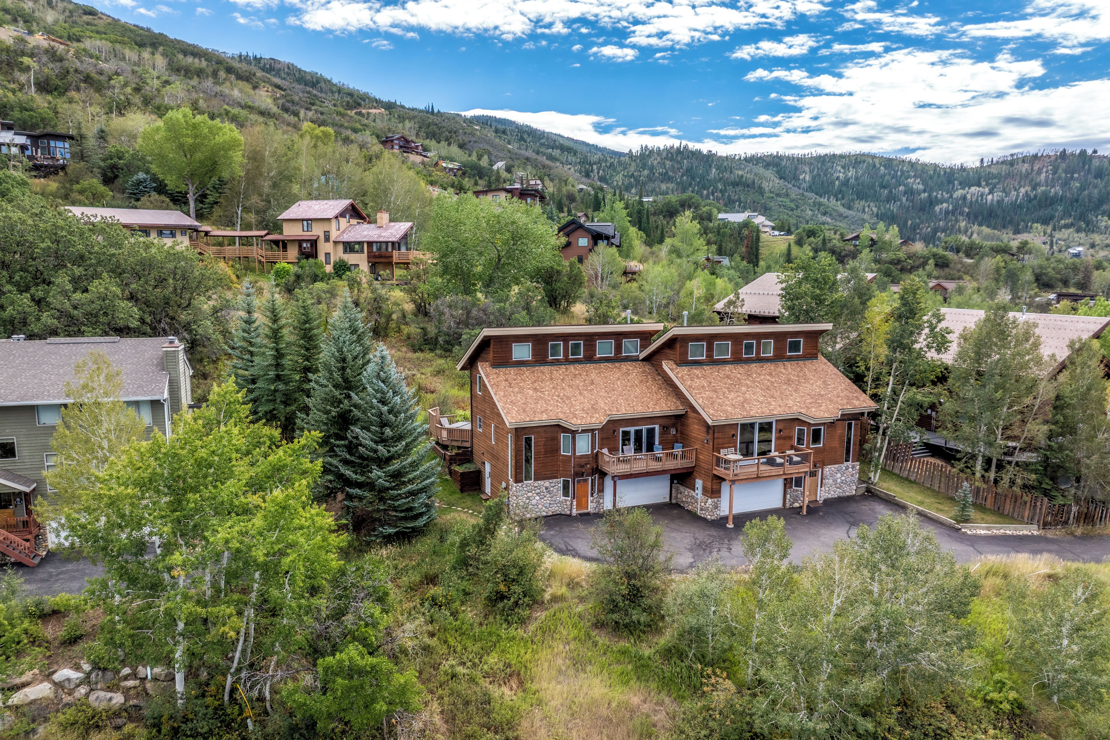 A two-story house with a stone foundation, a large garage, and a deck.