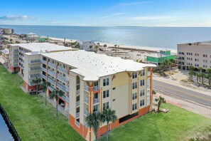 A multi-story hotel with balconies, a beach view, and a parking area.