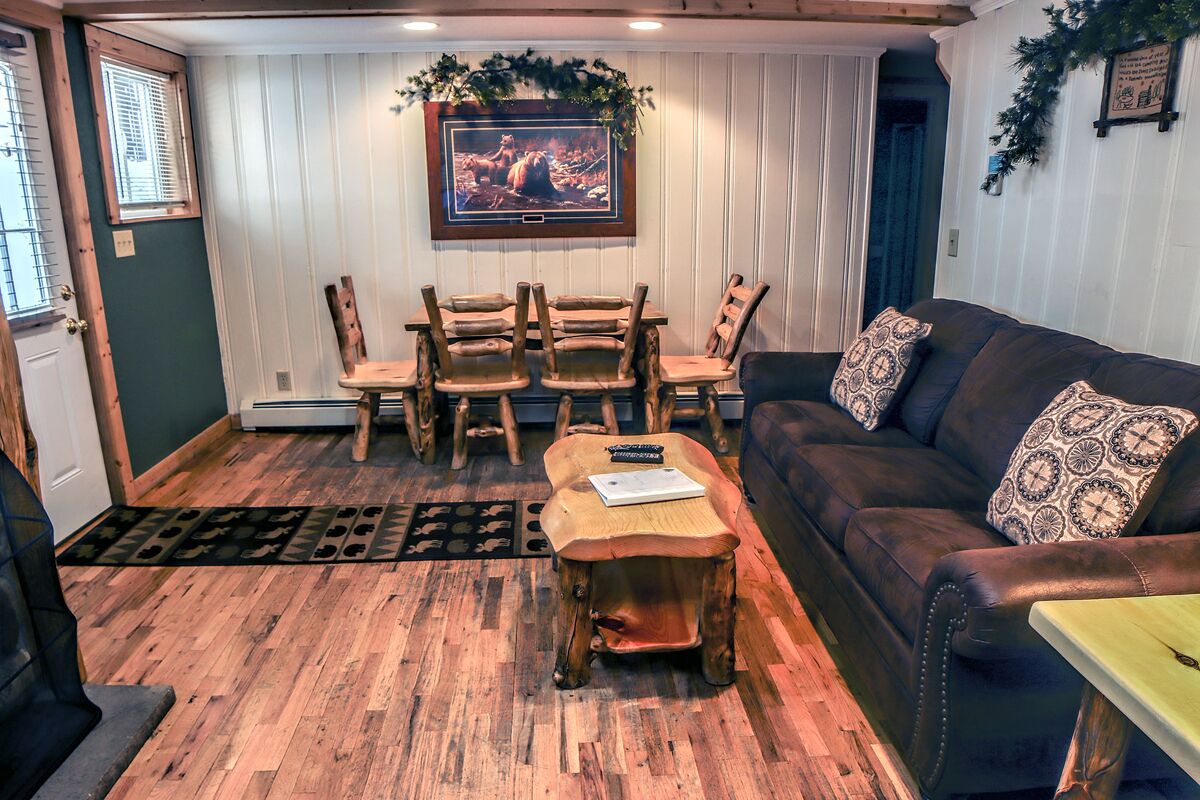 Ein gemütliches Wohnzimmer mit einem Holztisch, einer Ledersofa und einem Essbereich mit Holzkästen.