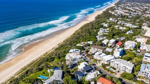 Vista aérea de una zona residencial costera con casas, una playa y una piscina.
