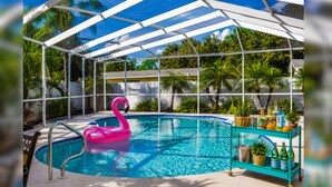 Et poolområde med et glasindhegning, en lyserød flamingo-svømmebåd og en vogn med flasker.