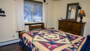 Une chambre à coucher avec un lit, une commode, une fenêtre avec des rideaux et un miroir.