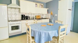 Cocina compacta con armarios blancos, estufa y mesa de comedor con cuatro sillas.