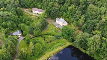 An aerial view of a lakeside property with two houses, a winding road, and dense forest.