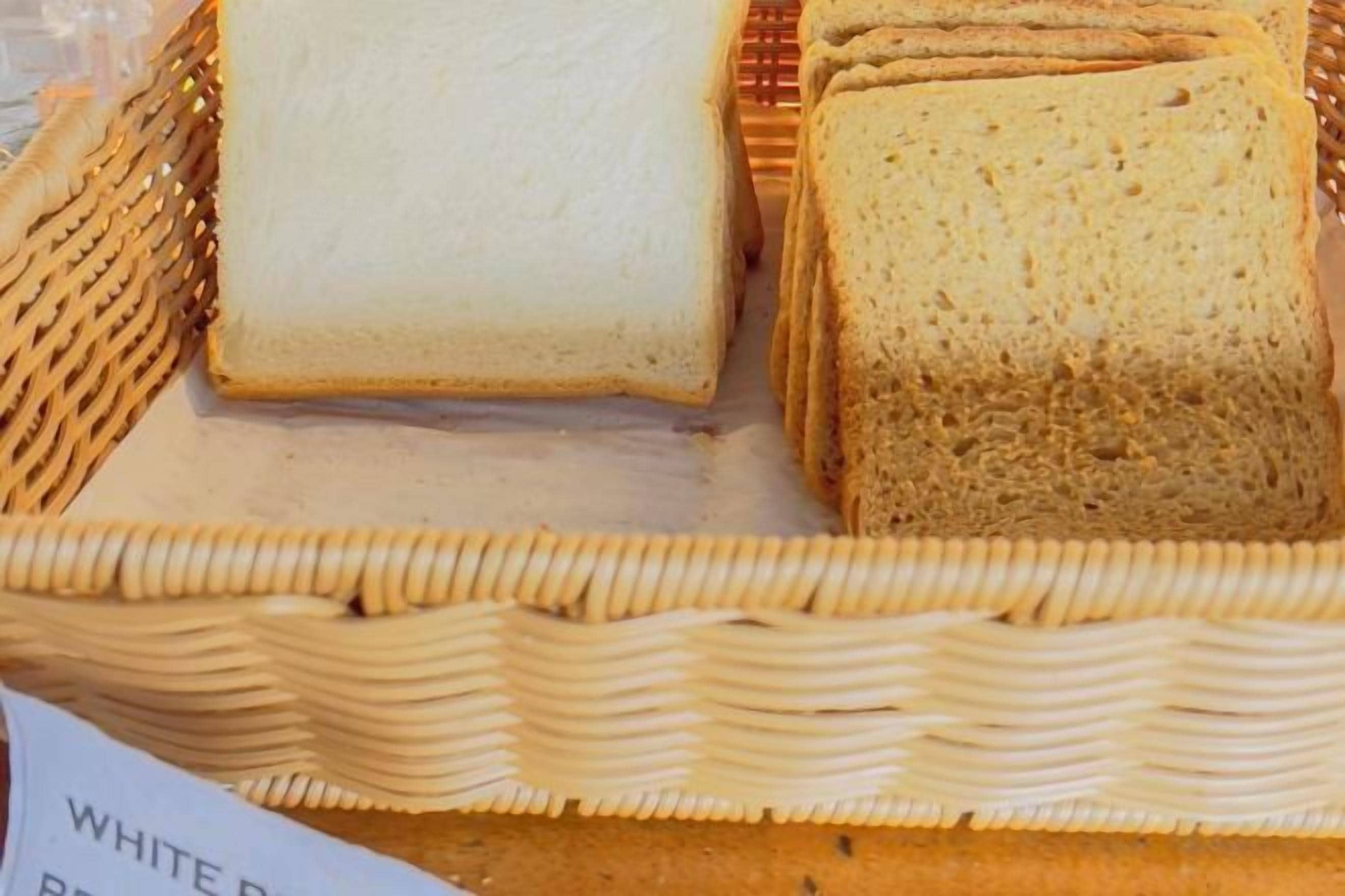 Una cesta con rebanadas de pan blanco y integral.