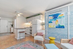 Una cocina moderna con armarios blancos, una barra y un cuadro abstracto y colorido en la pared.