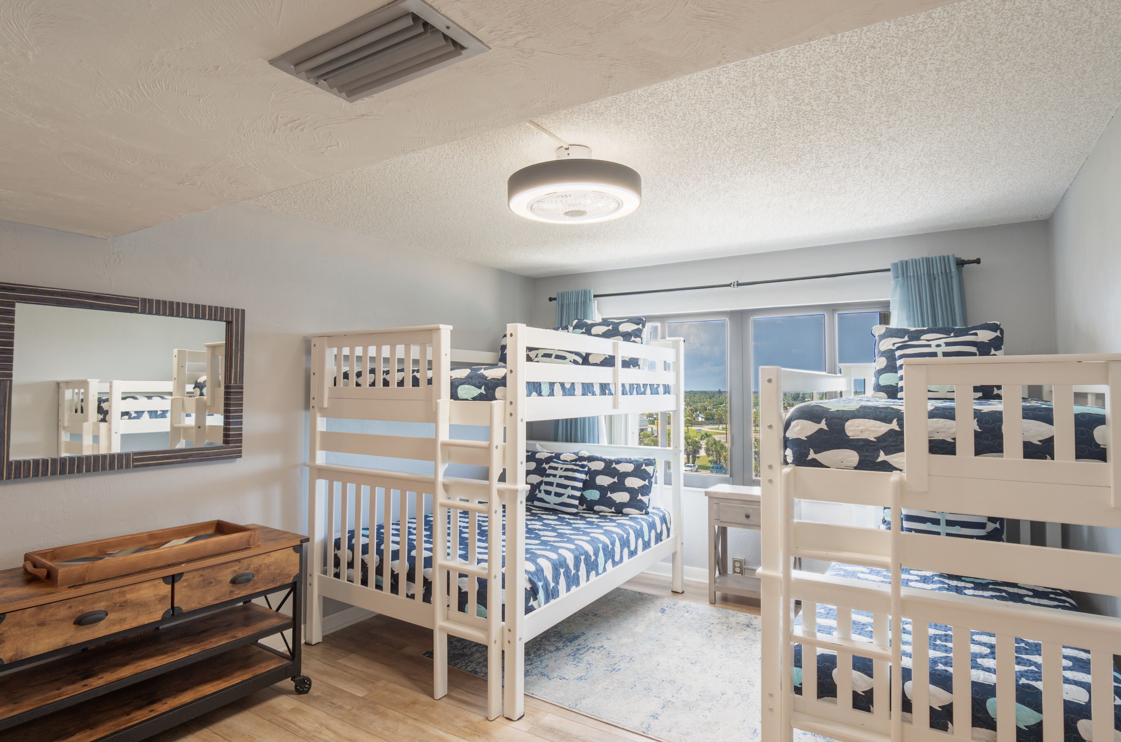 Un dormitorio con literas, un aparador de madera, un espejo y una ventana con vistas.