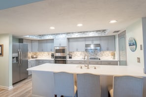 A modern kitchen with a central island, stainless steel appliances, and light blue cabinetry.