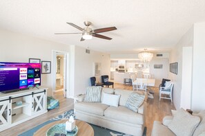 A modern living room with a television, sofa, and dining area.