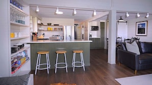 Un grand espace de vie comprenant une cuisine, une table à manger et un coin bar avec des tabourets.