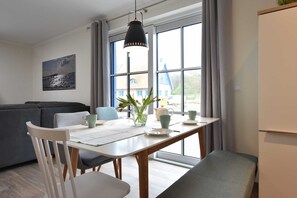 A modern dining area with a white table, chairs, and a hanging light fixture.
