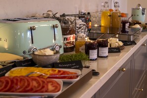 A buffet setup with various food items, including sliced tomatoes, cheese, and condiments.