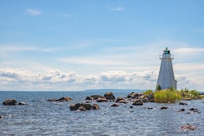 A lighthouse on a rocky shoreline with clear skies.