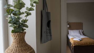 A room with a bed, a wall-mounted bag, and a large woven plant.