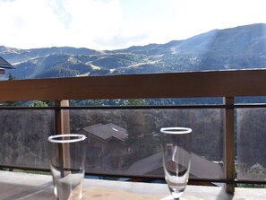 A table with two empty glasses and a view of a mountain landscape through a window.
