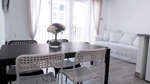 Un comedor con una mesa de madera oscura, sillas blancas perforadas y un jarrón de flores.