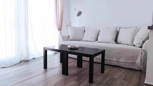 Una sala de estar con sofá, mesa de centro y lámpara.