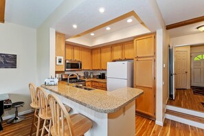 A modern kitchen with wooden cabinets, a granite countertop, and stainless steel appliances.