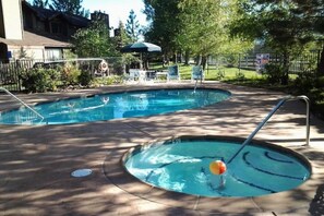 A swimming pool with a diving board and lounge chairs.