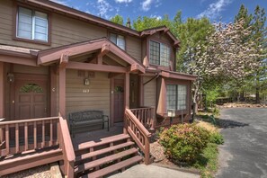 A two-story building with a porch, a bench, and a staircase leading to the entrance. - Amazing 3BR/2BA Lakefront Condo, WiFi, Outdoor Heated Spa, FREE Kayak/Bicycle Rental! (Big Bear Lake)