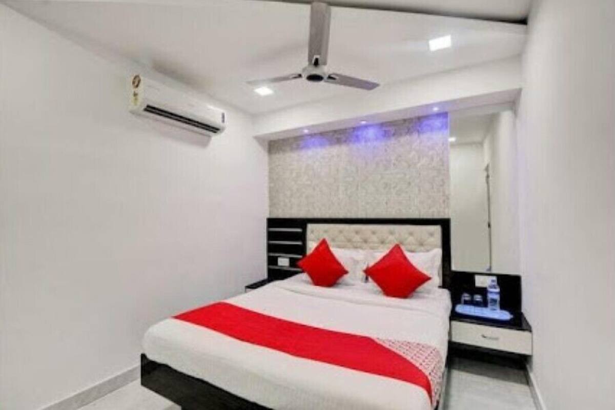 A modern hotel room with a bed, a nightstand, an air conditioning unit, and a ceiling fan.