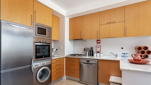 Una cocina moderna con electrodomésticos de acero inoxidable, armarios de madera y encimera de mármol.