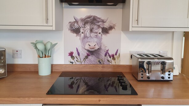 A kitchen with a modern induction cooktop, a toaster, and a wall-mounted light switch. - Inviting 2-bed Barn With hot tub Near Muirkirk (Cumnock)