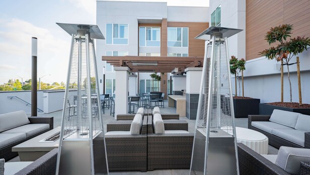Une terrasse sur le toit avec des sièges extérieurs, une pergola et un bâtiment moderne en arrière-plan.