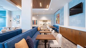 Un restaurant moderne avec des sièges bleus, des tables blanches et un plafond en bois.