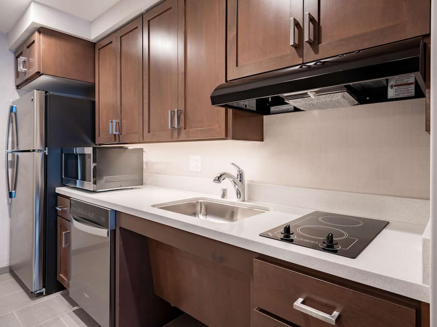 A modern kitchen with stainless steel appliances, a double sink, and wooden cabinets.