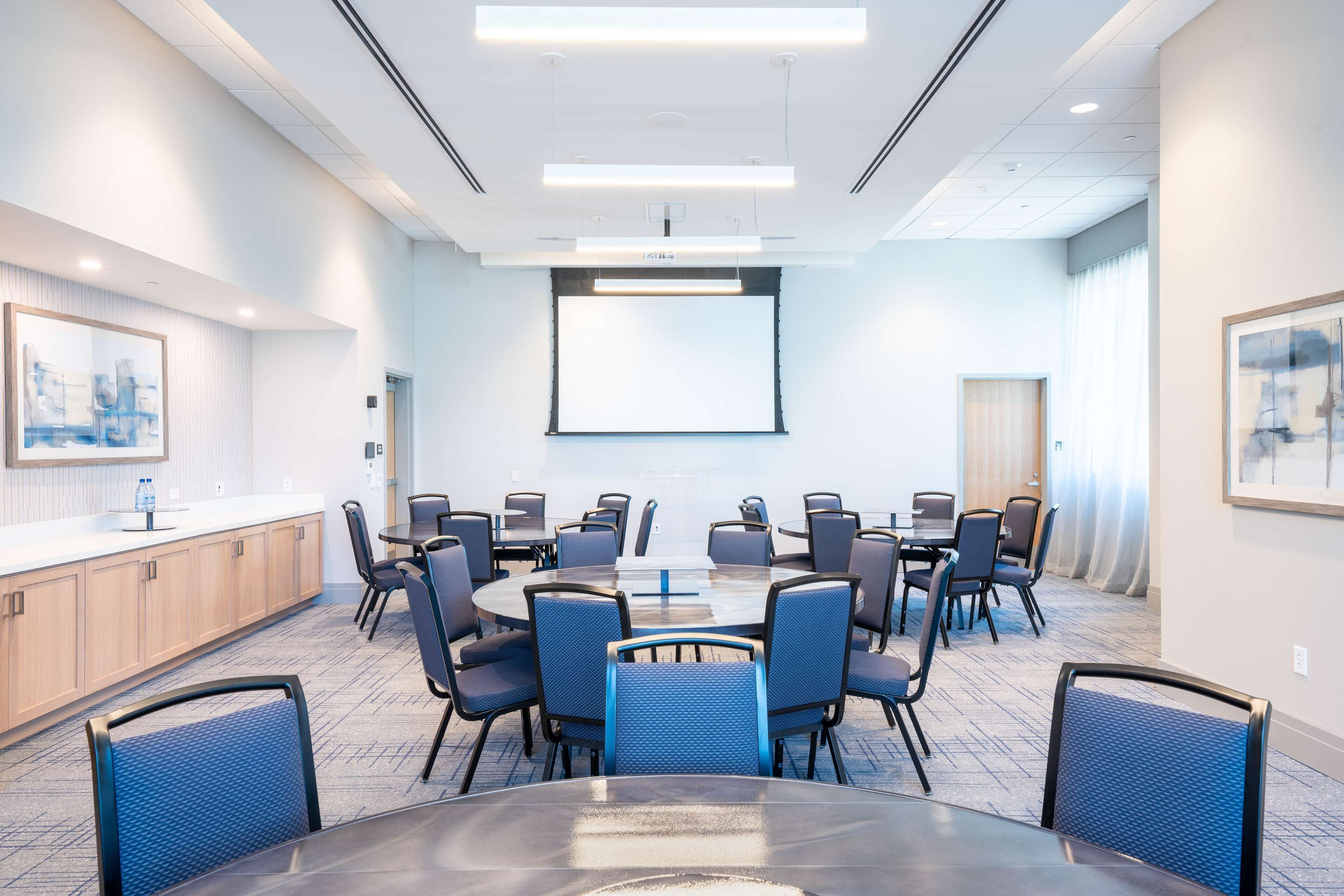 A conference room with a large table, chairs, a projector screen, and a whiteboard.