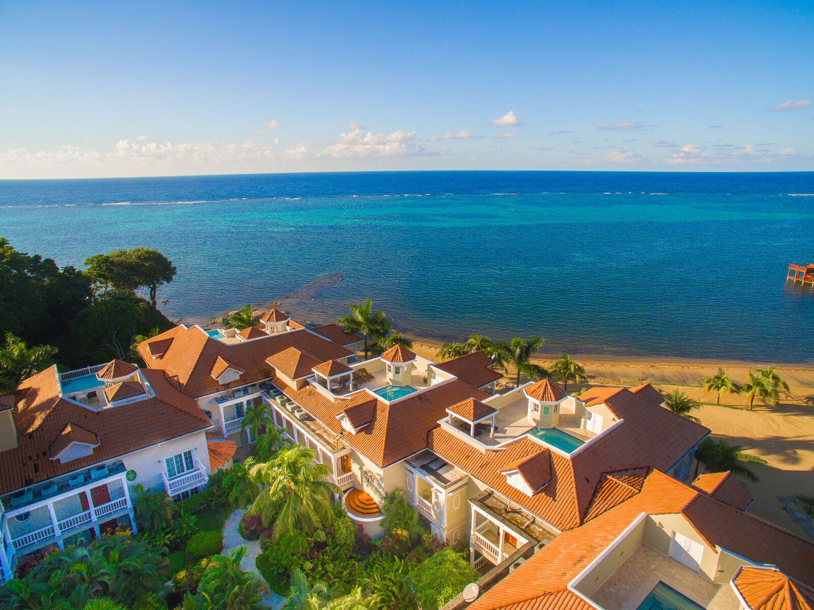 Un resort con varias edificaciones, piscina y vista a la playa.
