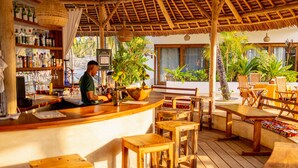 A bar area with wooden furniture and a thatched roof. - Aluna Paje (Paje)