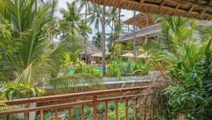 A tropical resort with a pool, palm trees, and a thatched-roof structure. - Aluna Paje (Paje)