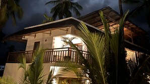 A night scene with a moonlit sky, palm trees, and a building with a balcony. - Aluna Paje (Paje)