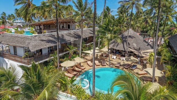 A resort with a pool surrounded by palm trees and thatched-roof structures. - Aluna Paje (Paje)