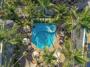 An aerial view of a resort with a central swimming pool surrounded by palm trees and sun loungers. - Aluna Paje (Paje)