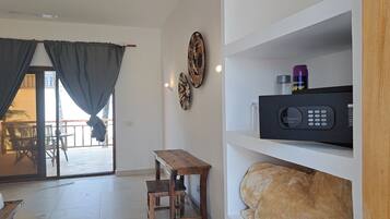 Una sala de estar con una mesa de madera, un sofá, un televisor en un estante y vistas a través de una puerta de cristal.