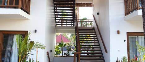 A modern building with a wooden staircase, white walls, and a thatched roof.