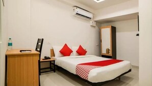 Ein Hotelzimmer mit Bett, Schreibtisch, Klimaanlage und Spiegel.